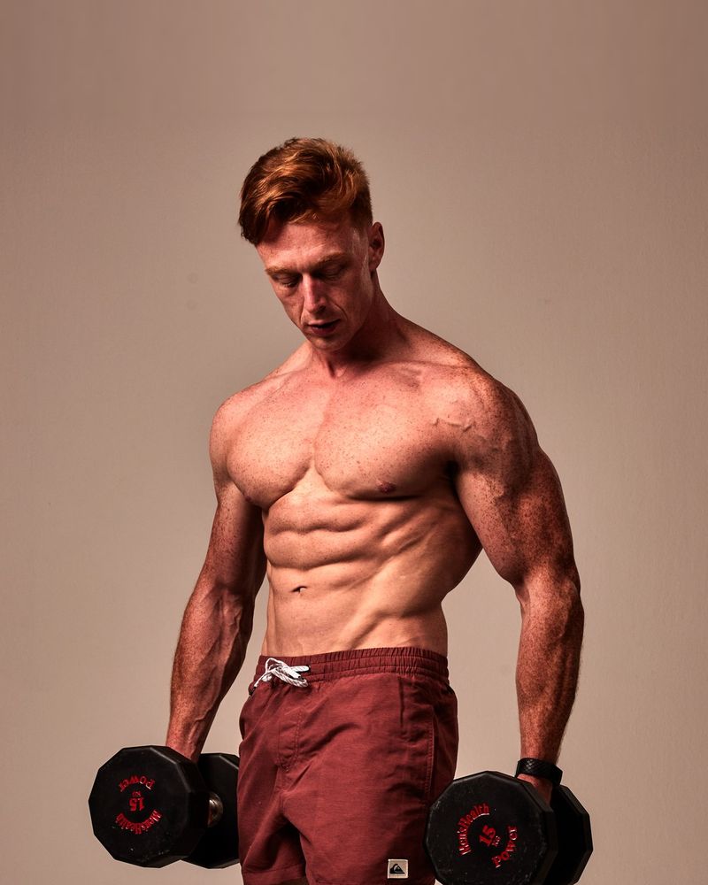 Vincent van Haren in 2022, gespierd en met twee dumbbells in de fotostudio van Men's Health